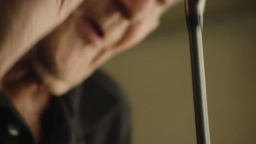 The video begins with a closeup on a set of golf clubs an elderly mans hand reaches into the bag pulls out a club and raises it the shot then cuts to a closeup of the mans face showing him looking down at the club with a thoughtful expression