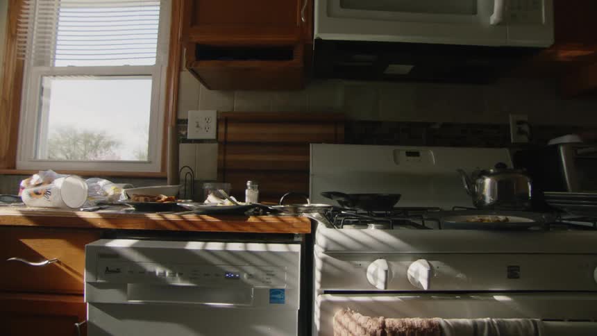A kitchen has dirty dishes and leftover food on the counter