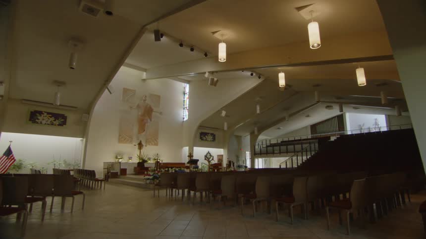 Interior of a large empty church with rows of chairs and religious symbols