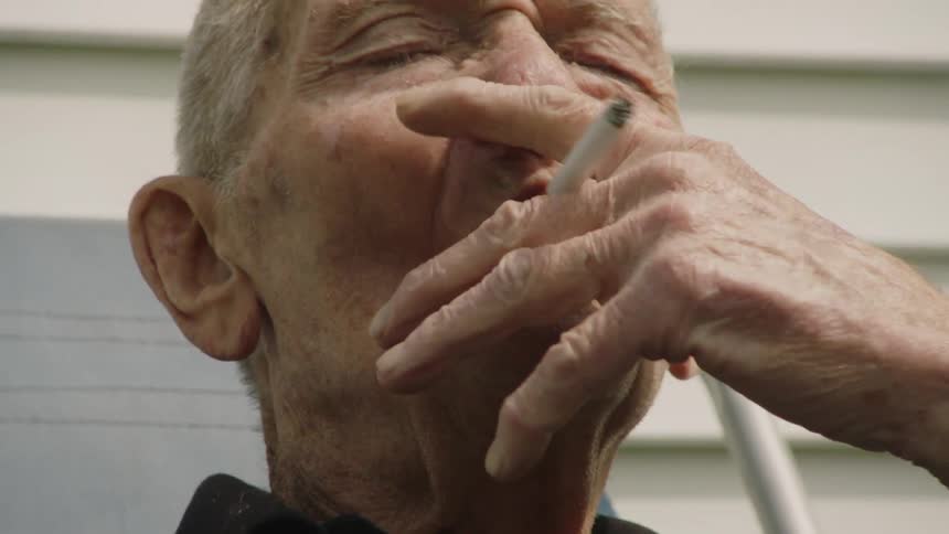 An old man smoking outside