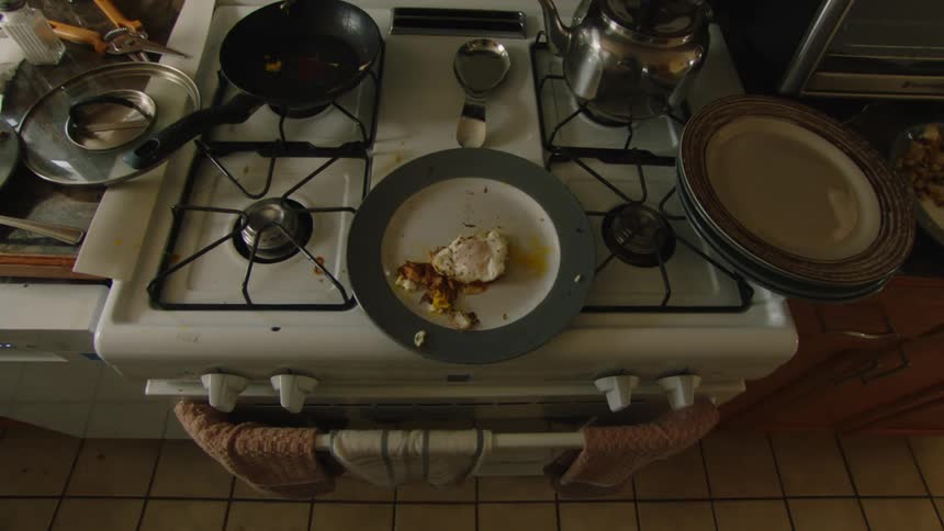 A dirty kitchen stove with used dishes and leftover food