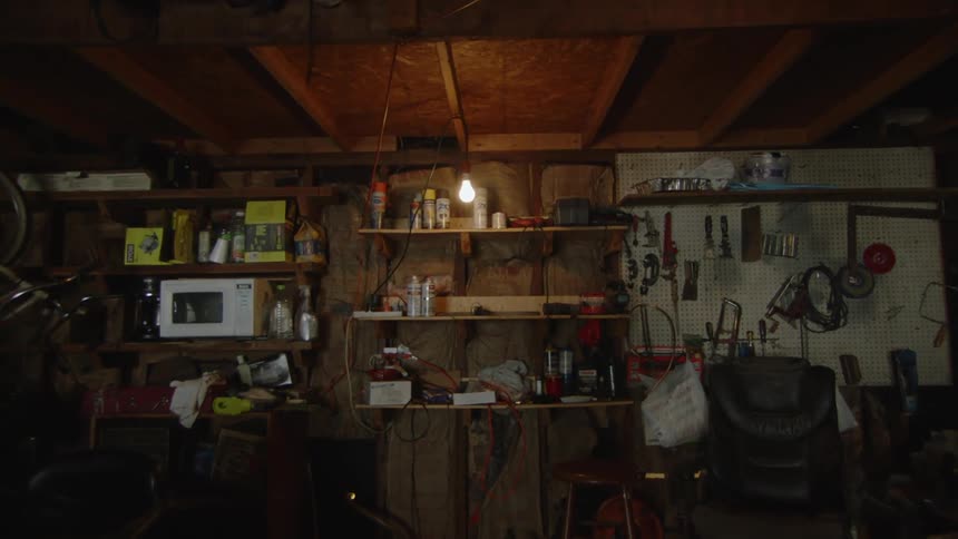 A dimly lit cluttered garage workshop filled with tools wiring and repair equipment