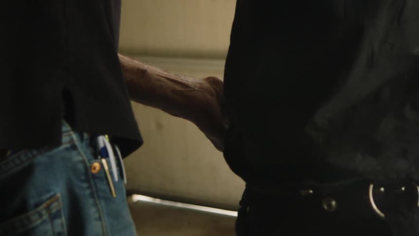 The video shows an elderly man working on something then the camera focuses on his hands as he reaches for a golf club he pulls the club out of a golf bag revealing a collection of other golf clubs
