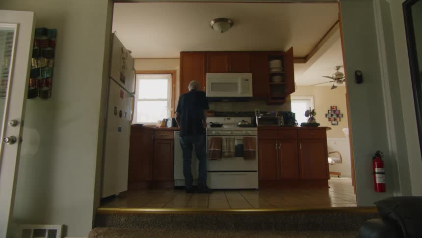Elderly man cooks in the kitchen in his home during the daytime