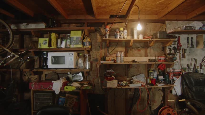 Interior of a cluttered storage room with shelves filled with various tools