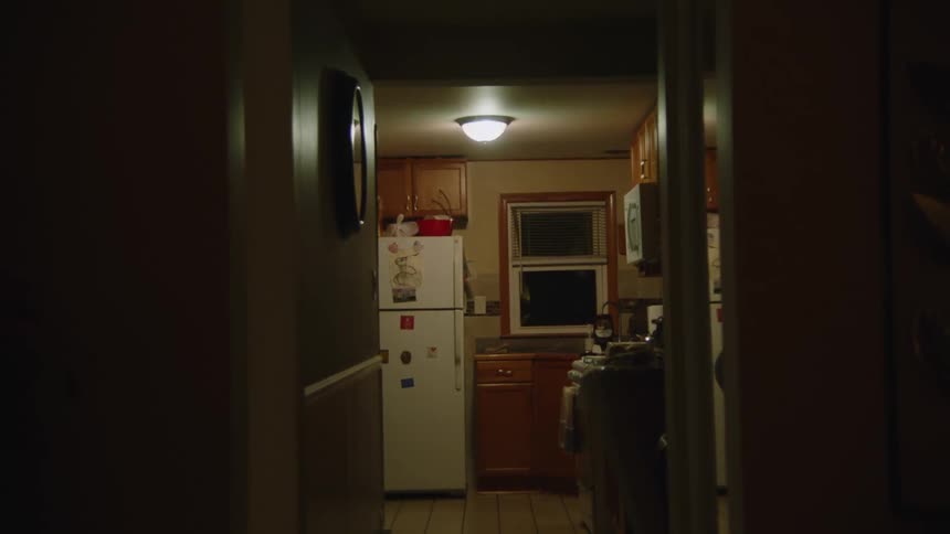 A view into a small kitchen from a dimly lit hallway at night
