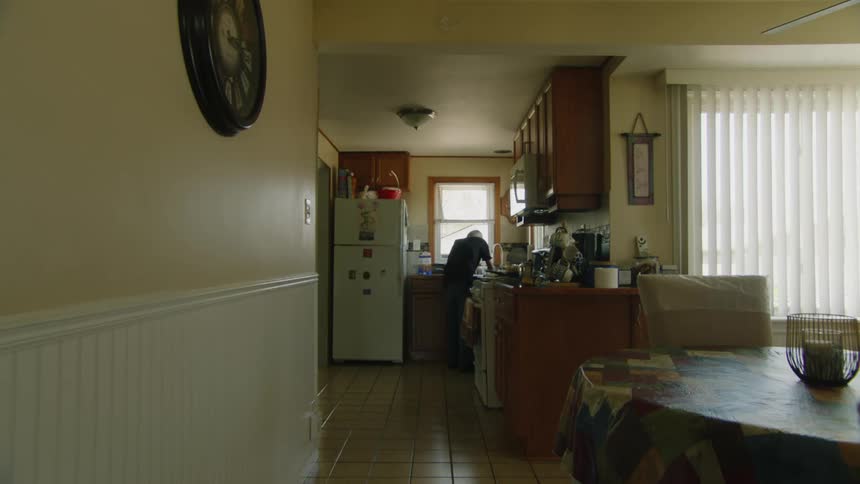 Man performs tasks in the kitchen lit by natural light from the window
