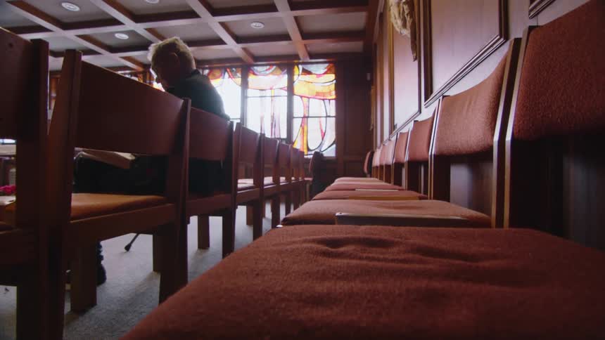 A man sits in a chair reading something inside of a church