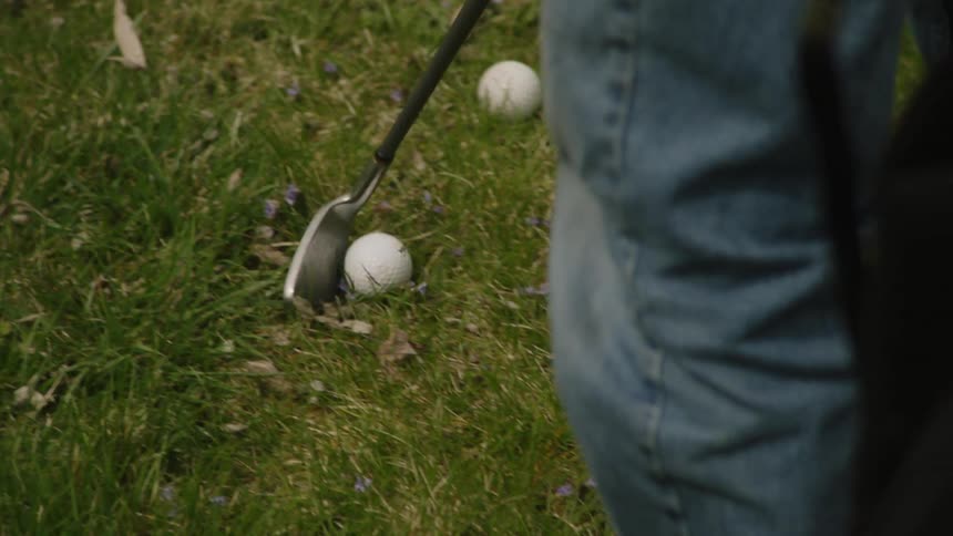 The video shows an elderly man with white hair wearing a red polo shirt walking with a golf bag the shot focuses on him placing the golf bag on the ground and the clubs are visible in the bag