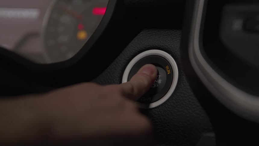 A person presses the start button to start a car ready to drive