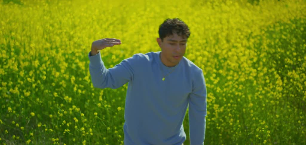 Young man dancing in a field of yellow flowers