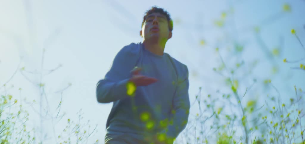 A man is performing slow dance moves in a bright yellow flower field