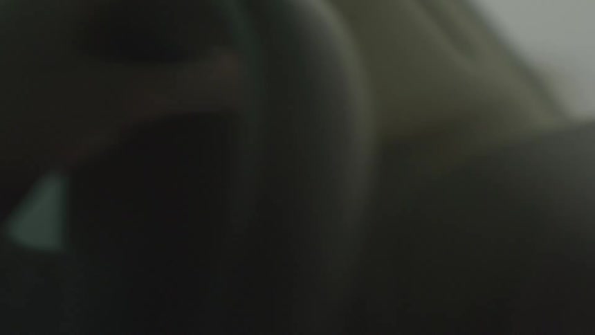 The video shows an extreme closeup of a persons hand drawing on a tablet or electronic device in the dark the faint glow of the screen and a small red indicator light are the only sources of illumination creating a lowlight intimate view of the crea