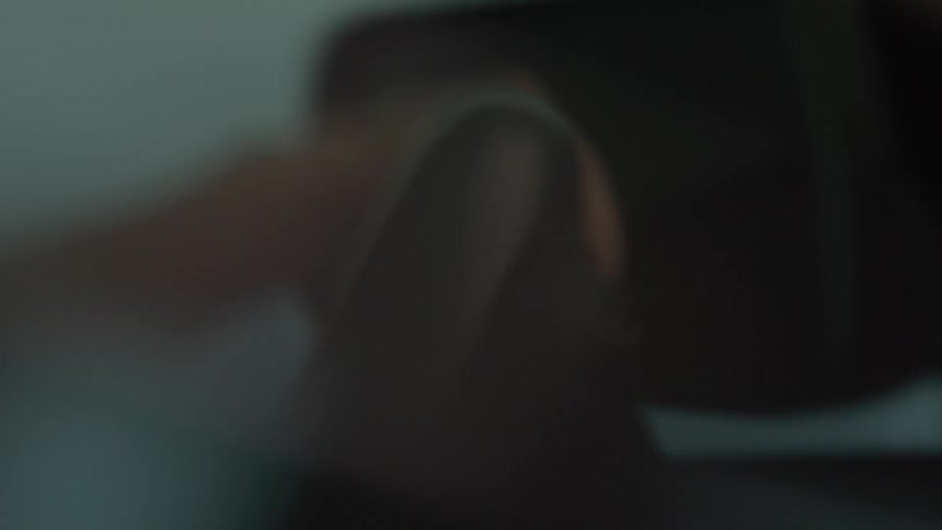 A blurry out of focus close view shows a person driving with their hand turning a steering wheel