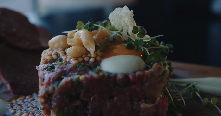 A closeup of a gourmet dish with detailed toppings and garnish