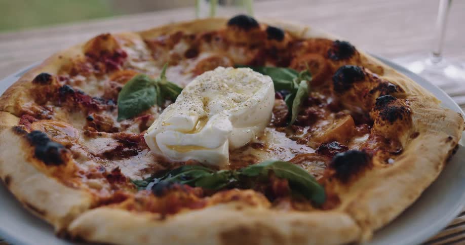 Pizza on a wooden table with wine glasses