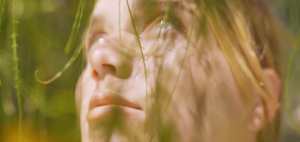 Face lit by sunlight seen through blurred branches and leaves