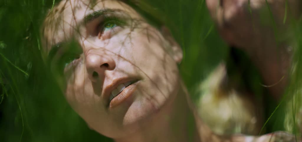 Woman among green leaves of a tree looking up