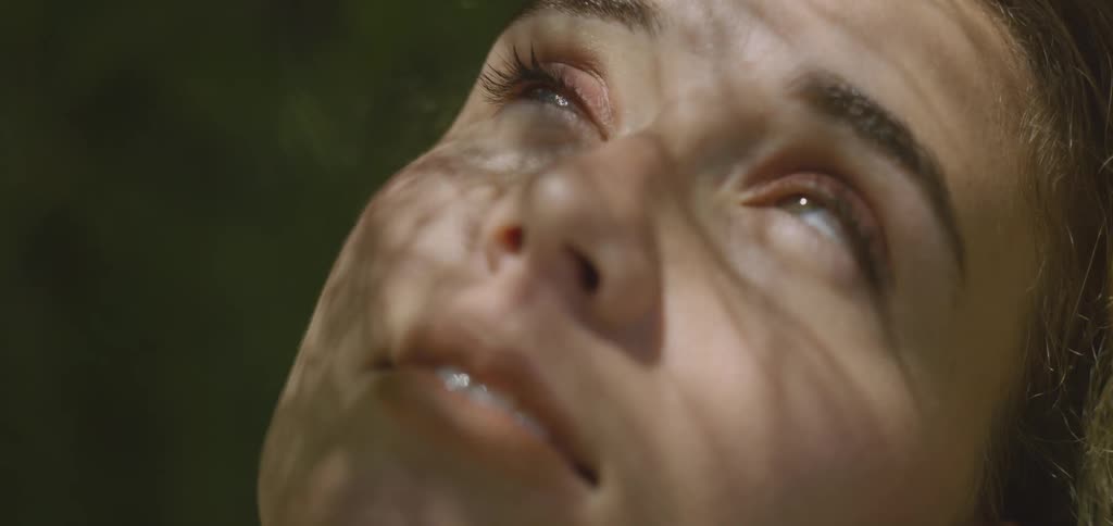 Woman outdoors looking up with sun reflection