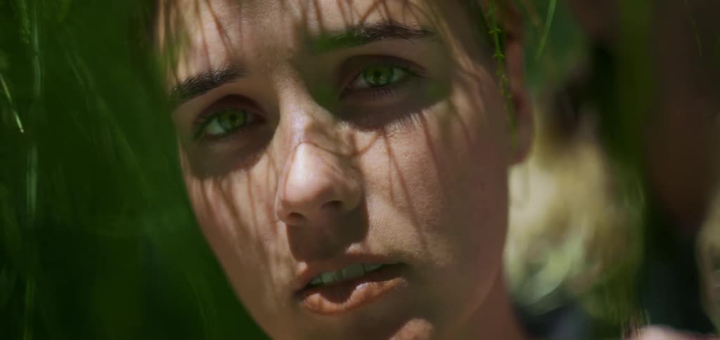 Female face in closeup is covered with leaf shadows cast by sunlight