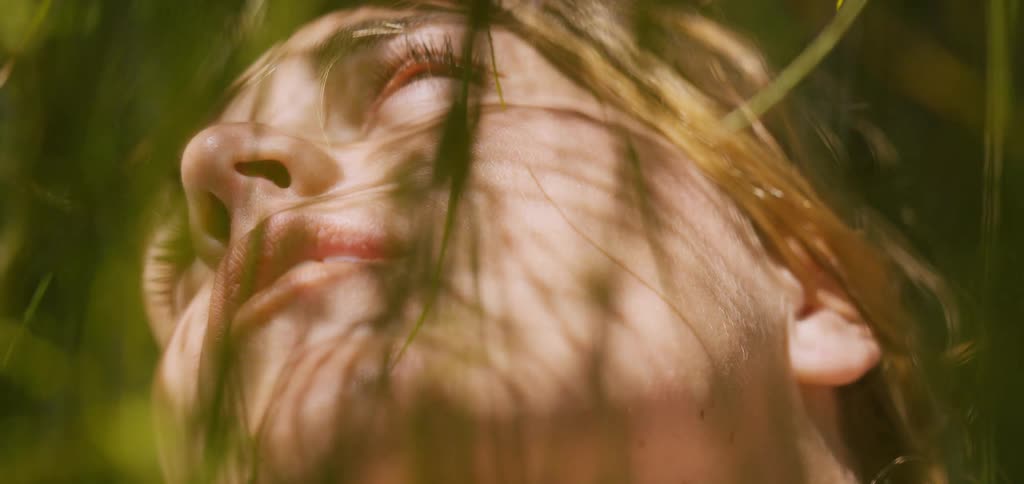 Face lit by sunlight appears among shadows cast by leaves