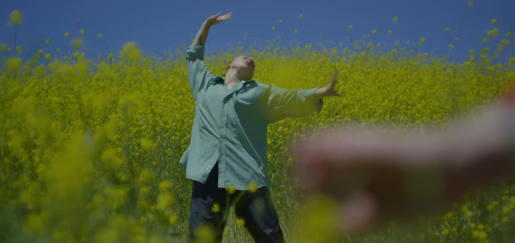 Person in the foreground holding a yellow flower and in the background another person dancing