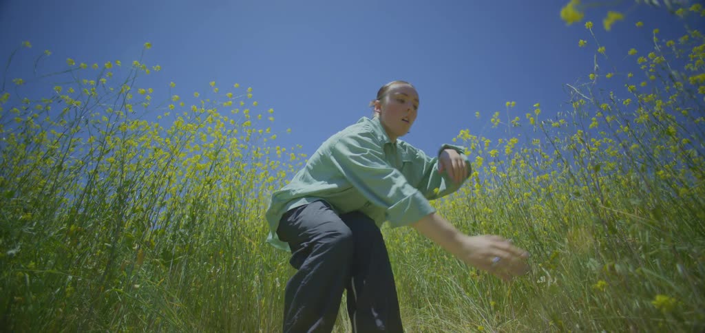 Woman in shirt dancing among yellow flowers in a field