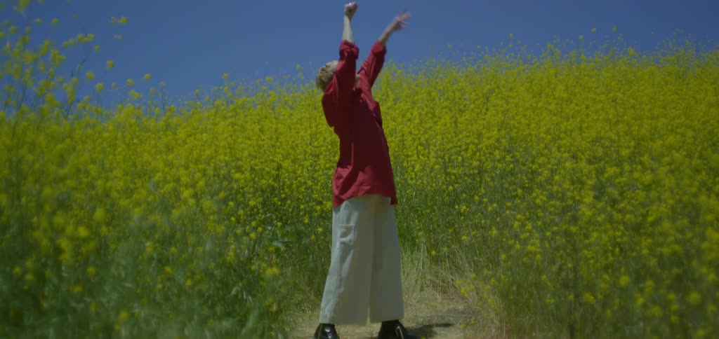 Blonde woman dancing in the middle of a field of yellow flowers