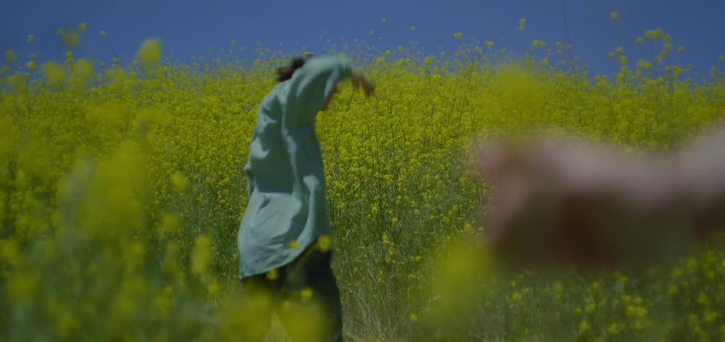A woman does tai chi near the very tall grass