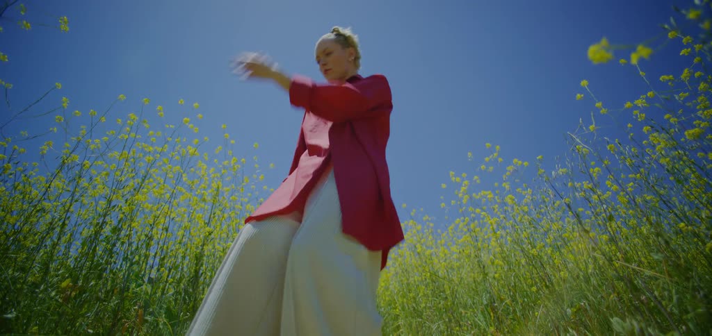 Blonde woman in a red tshirt dancing in a field of yellow flowers
