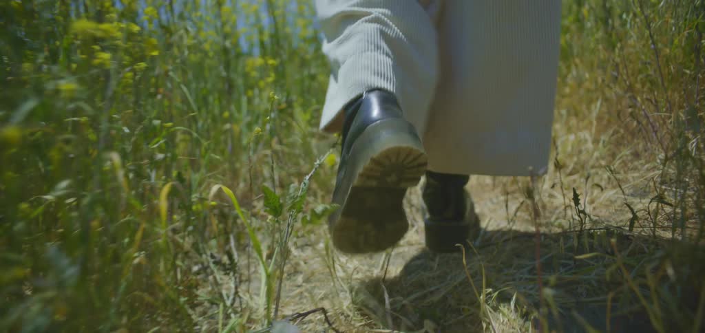 Legs of a person in black boots walking along a trail