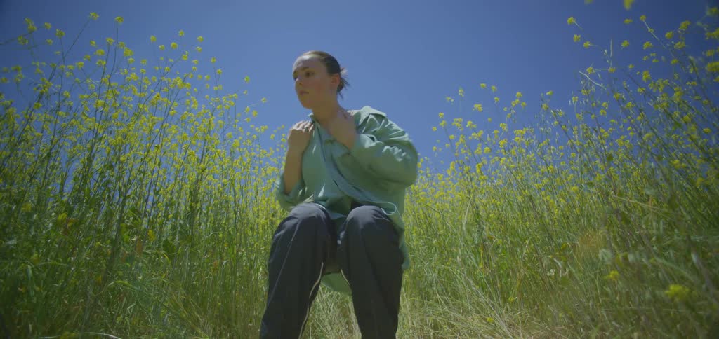 The woman is dancing in the tall flowers and grass