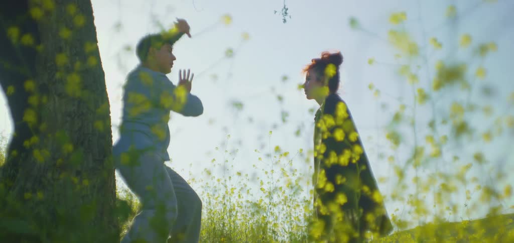 The woman stands by watching a man do tai chi by the tree