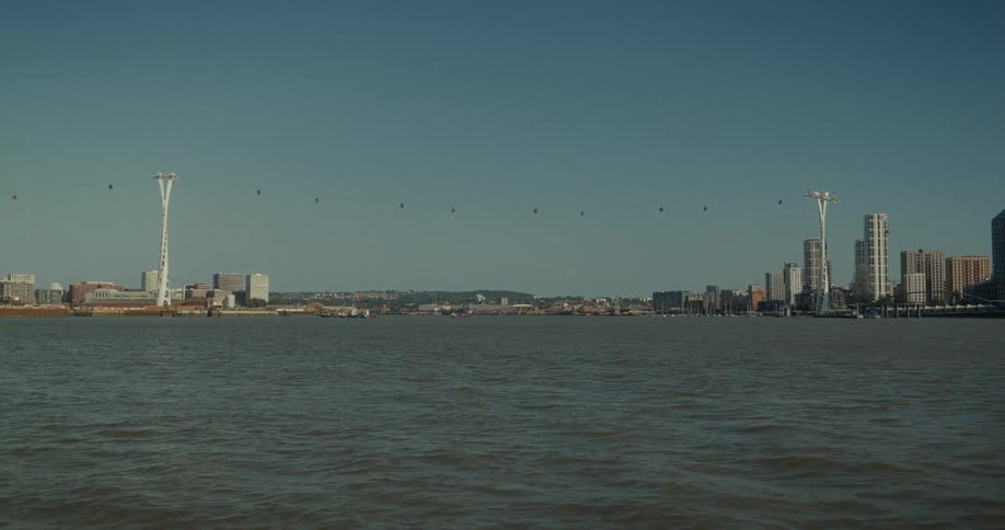 View of a coastal city with a cable car crossing over the water connecting two tall towers among modern buildings