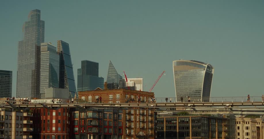 People walk across a long bridge that overlooks the city