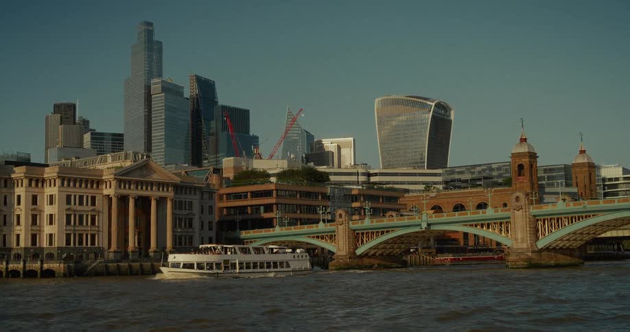 A steady shot of a modern city capturing the citys unique skyline and a tourist boat cruising on the water