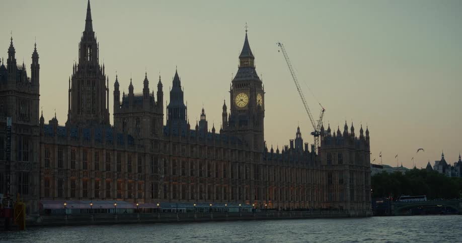 The video shows the palace of westminster in london england viewed from across the river thames the iconic big ben clock tower is visible with a construction crane behind it
