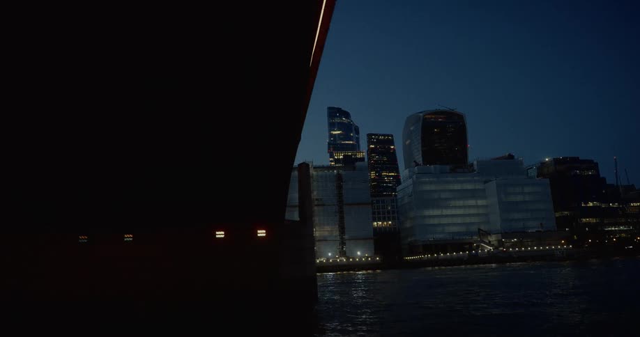 Lit bridge contrasts with illuminated skyscrapers at night in london