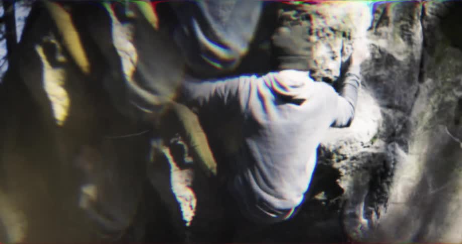 A young male falls while attempting to climb a rock outdoors during daytime