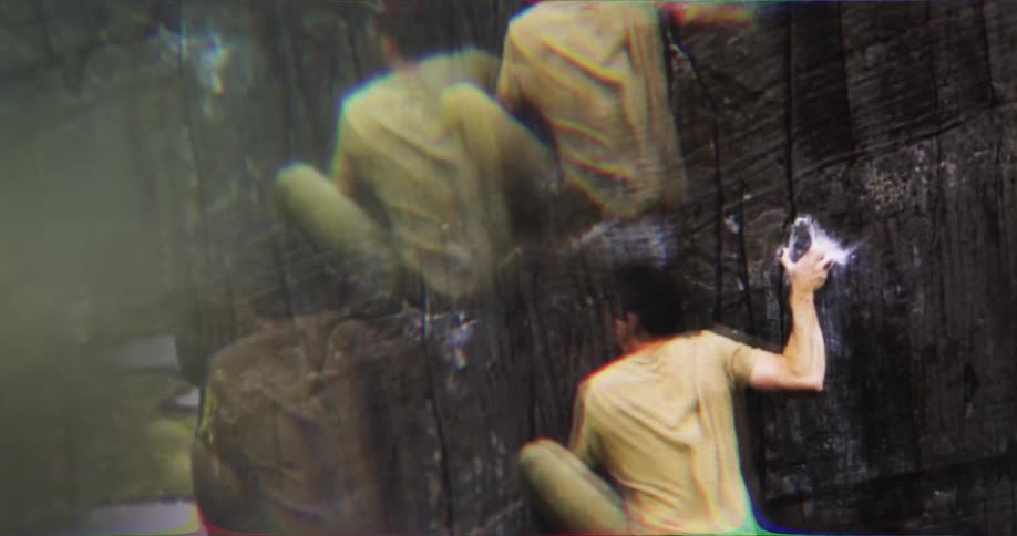 Climber in a yellow shirt ascends a rock wall using chalk on his hands