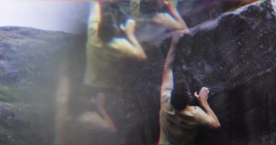 Climber with chalk on hands ascends a dark rock wall