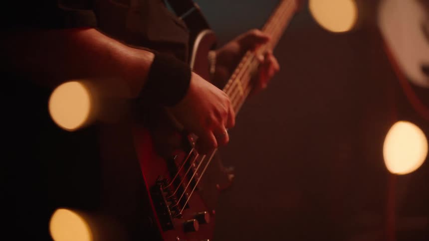 A man playing bass guitar on stage with a band
