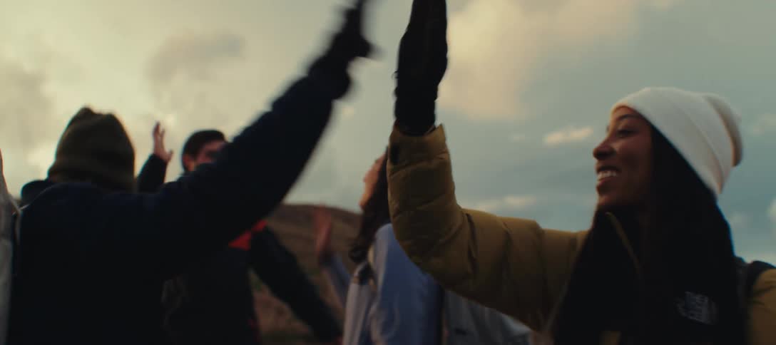 A shot of a diverse group of friends celebrating their success on a hike by highfiving each other on a mountain top