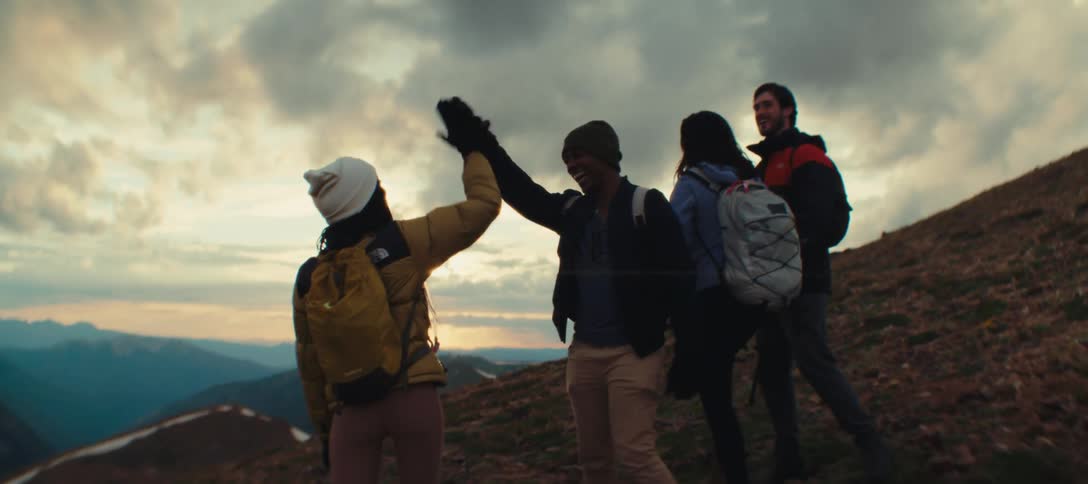 Group of hikers celebrating at the mountain top during sunset