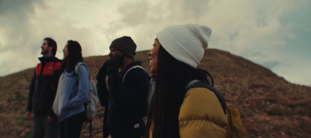 Group of four smiling friends take a break during a mountain trail hike