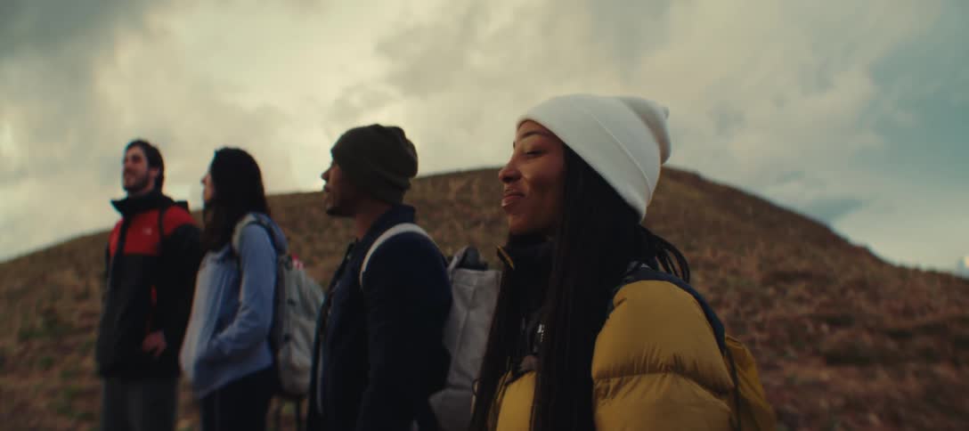 Group of four people looks at the landscape on a mountain with expressions of awe and satisfaction