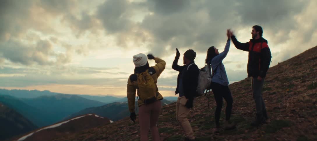 Group of four people watches the mountainous landscape at sunset
