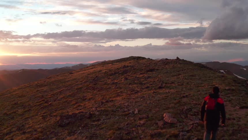 Four people walk toward the top of a hill during sunset