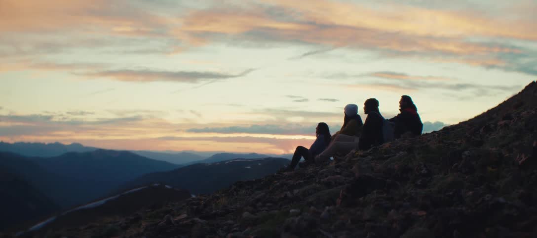 Four people sitting outside on a dark morning with an orange sky