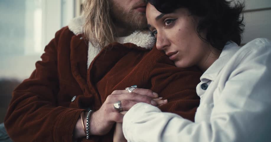A couple sits closely together comforting each other